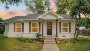 Ein eingeschossiges Haus mit Veranda, mittlerem Eingang und kleinem Vorgarten.