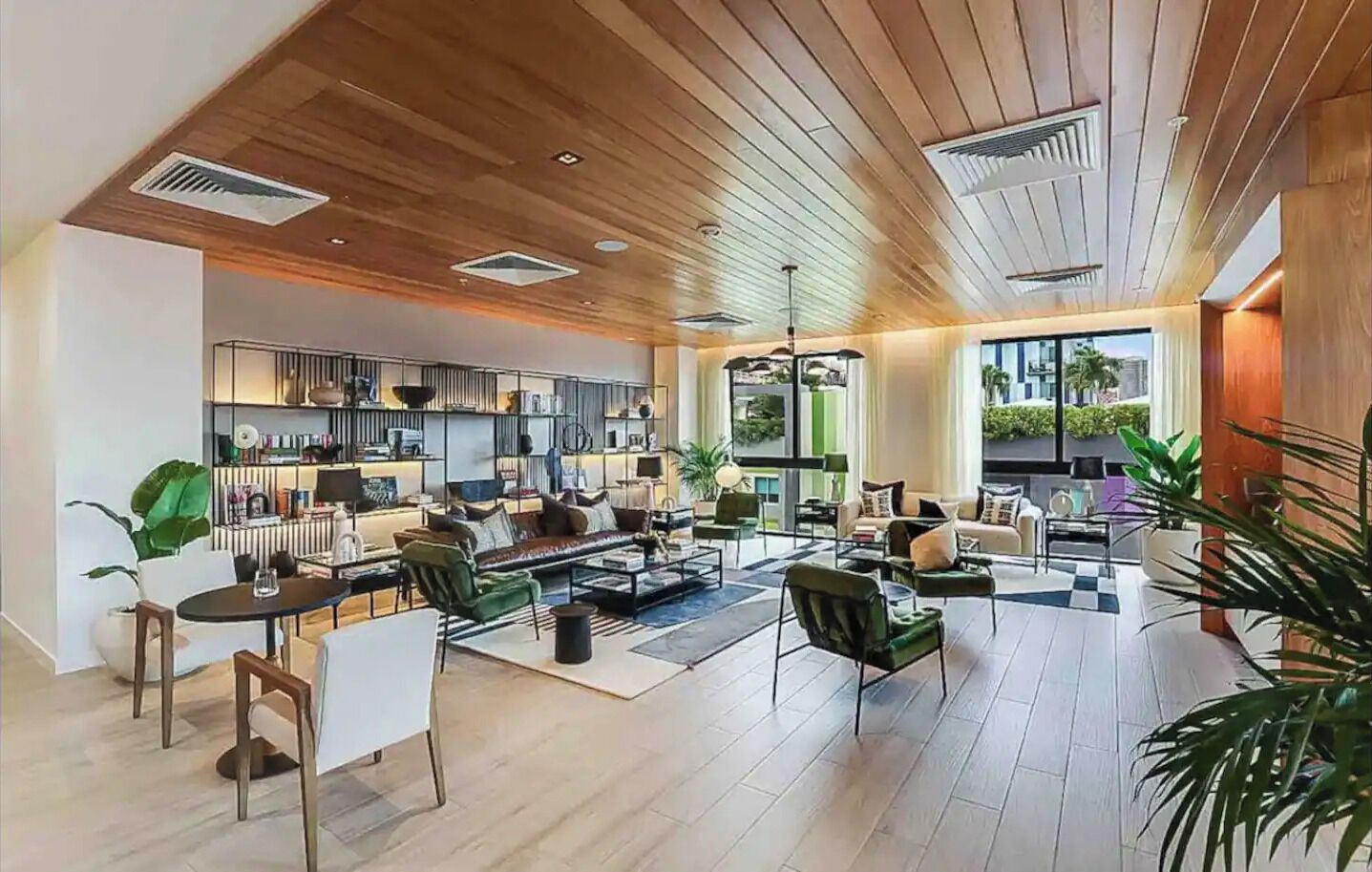 A spacious living area with a modern kitchen, large windows, and a high ceiling with wooden beams.