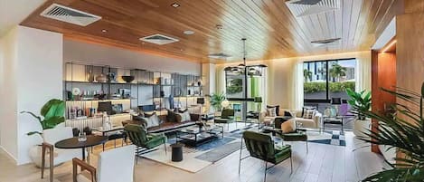 A spacious living area with a modern kitchen, large windows, and a high ceiling with wooden beams.
