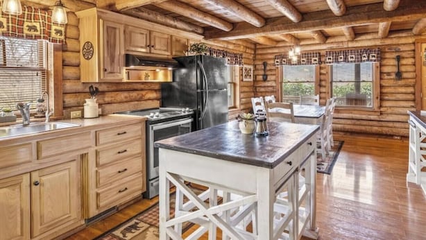 Une cuisine de style rustique, avec des meubles en bois, un îlot central et un grand réfrigérateur.