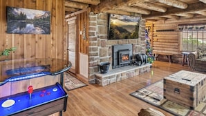 L’intérieur d’un chalet confortable, avec une cheminée en pierre, des poutres en bois et une table de baby-foot.