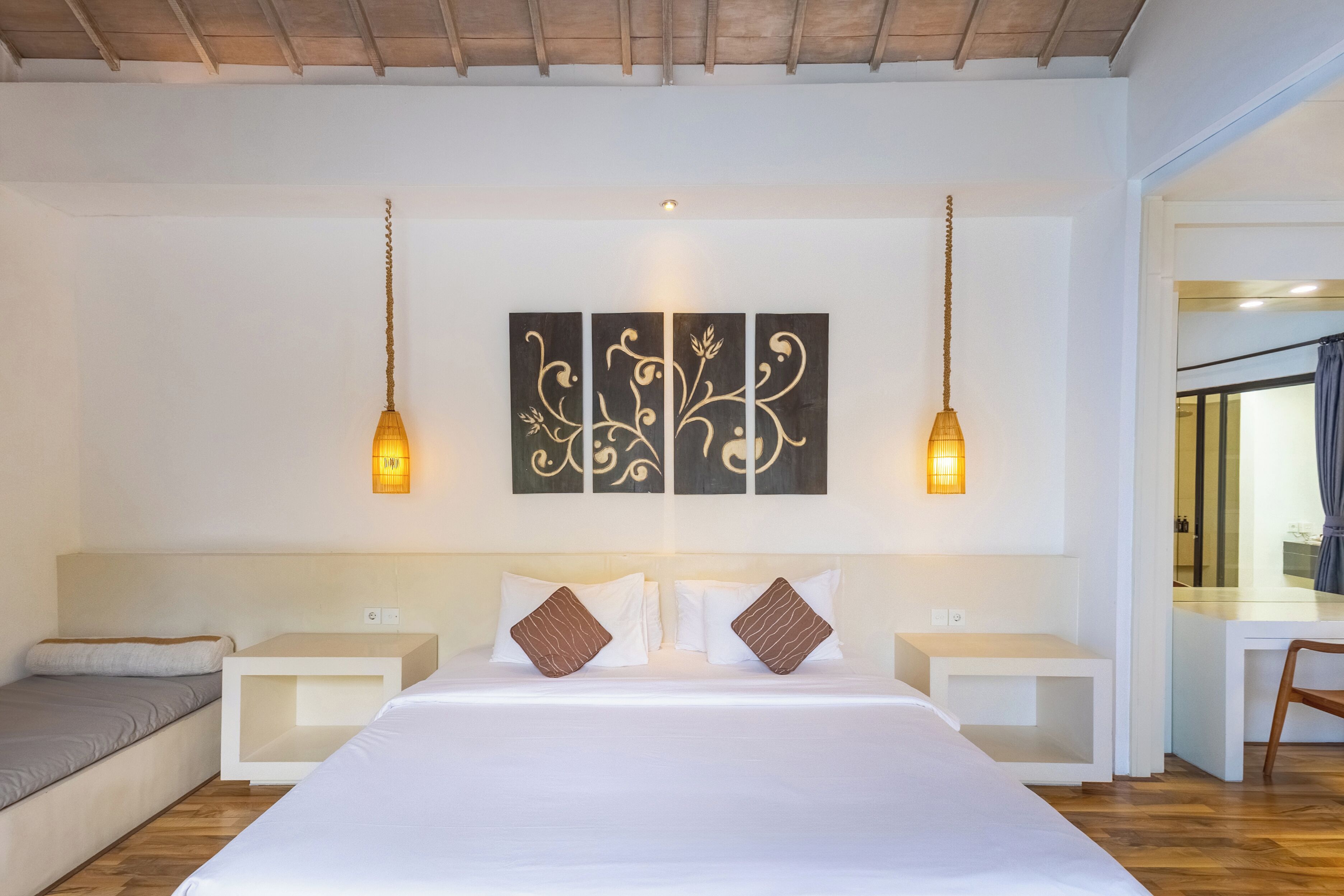 Ein Hotelzimmer mit einem großen Bett, zwei Nachttischen, einem Schreibtisch und einem Sessel.