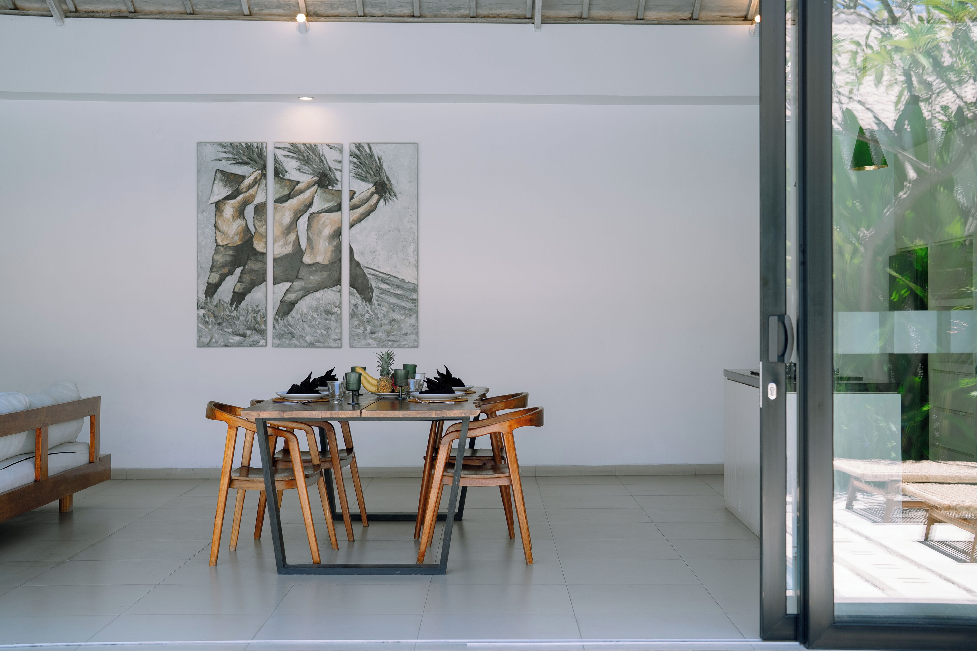 Comedor con una mesa, sillas, un cuadro en la pared y un ventanal corredero que da a un espacio exterior.