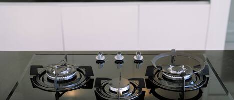 A modern kitchen with a gas stove, a sink, and white cabinets.
