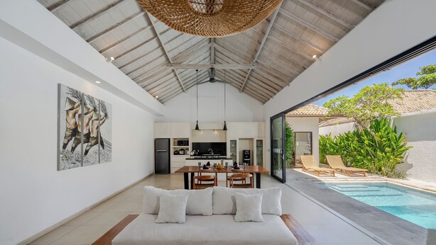 Un intérieur moderne comprenant un canapé, un coin repas, une cuisine et une vue sur la piscine.