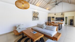 Un vaste espace de vie comprenant un canapé, une table basse et une table à manger, attenant à une cuisine au design moderne.