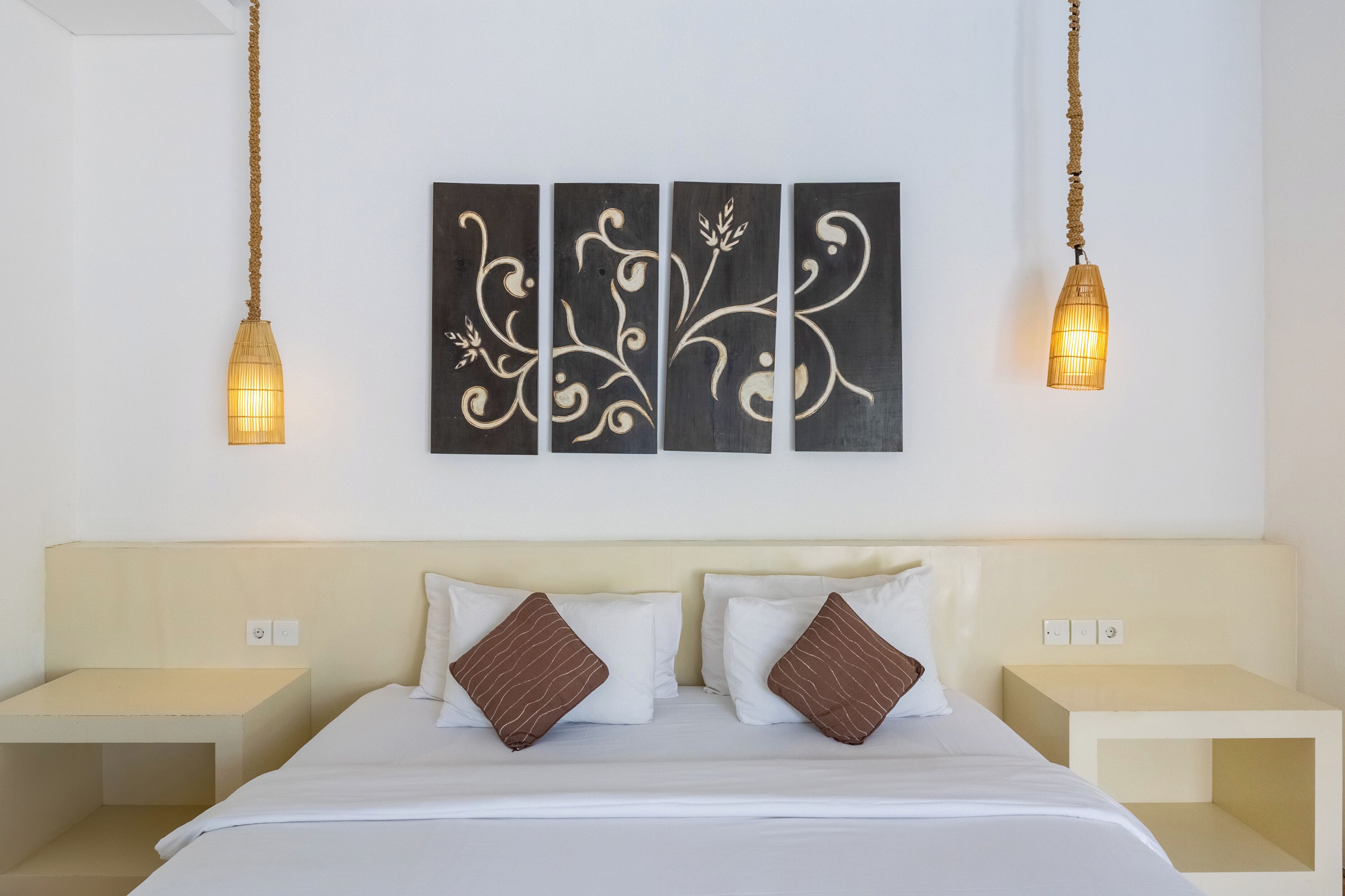 Ein Hotelzimmer mit einem Bett, zwei Nachttischen und einem an der Wand hängenden Kunstwerk über dem Bett.
