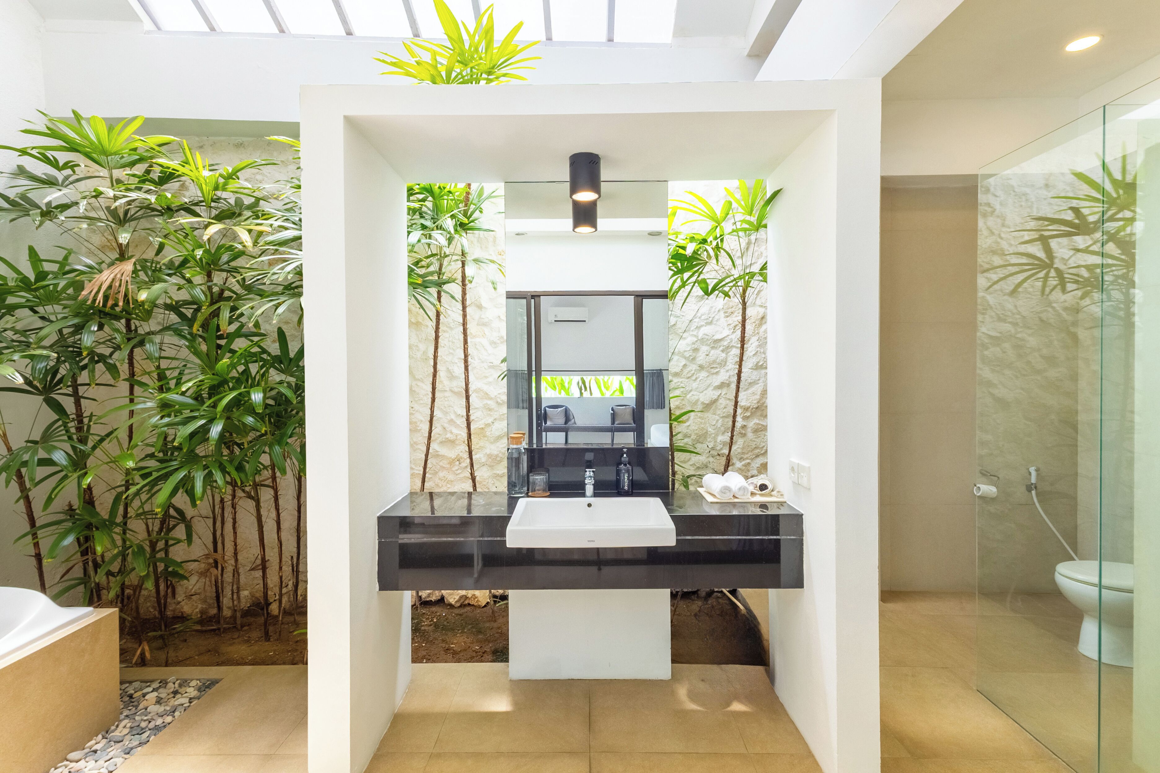 A modern bathroom with a black sink, white countertop, and a glass shower enclosure.