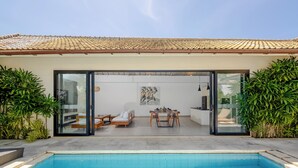 Une maison moderne dotée d’une piscine, d’un coin repas et d’un salon avec un canapé et une table.