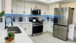 A modern kitchen with white cabinets, stainless steel appliances, a microwave, stove, and refrigerator. - Renovated 4BR Las Vegas Home Private Pool, BBQ Ping Pong Parking 20 min to Strip (Henderson)