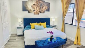 A bedroom with a large bed, a blue headboard, and a lion painting on the wall. - Renovated 4BR Las Vegas Home Private Pool, BBQ Ping Pong Parking 20 min to Strip (Henderson)