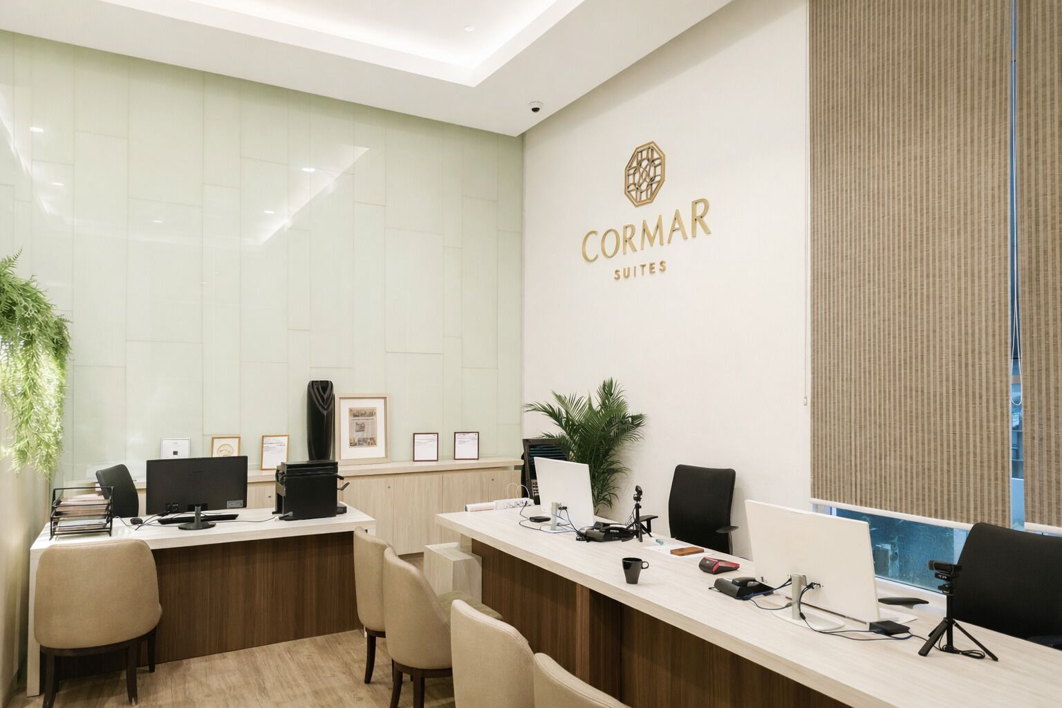 A modern office with a reception desk, computers, and framed certificates.