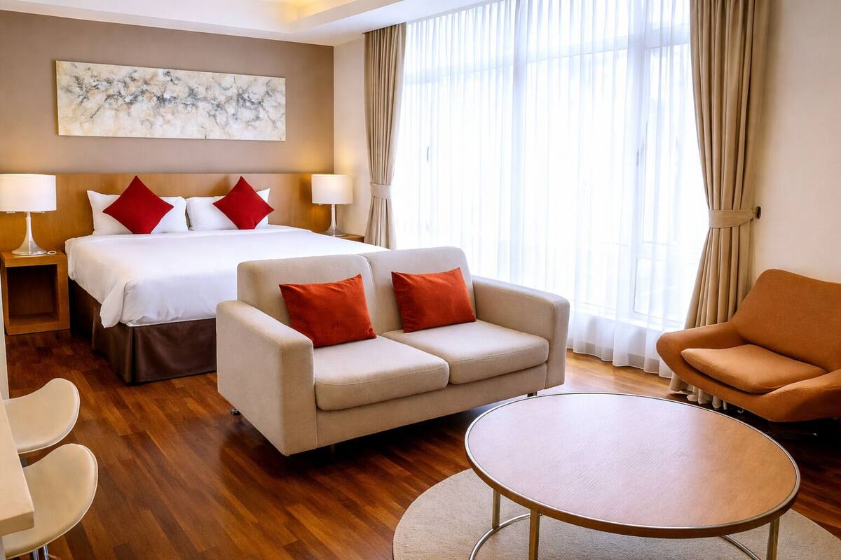 Une chambre d’hôtel avec un lit, deux canapés, une table ronde et un tableau au mur.