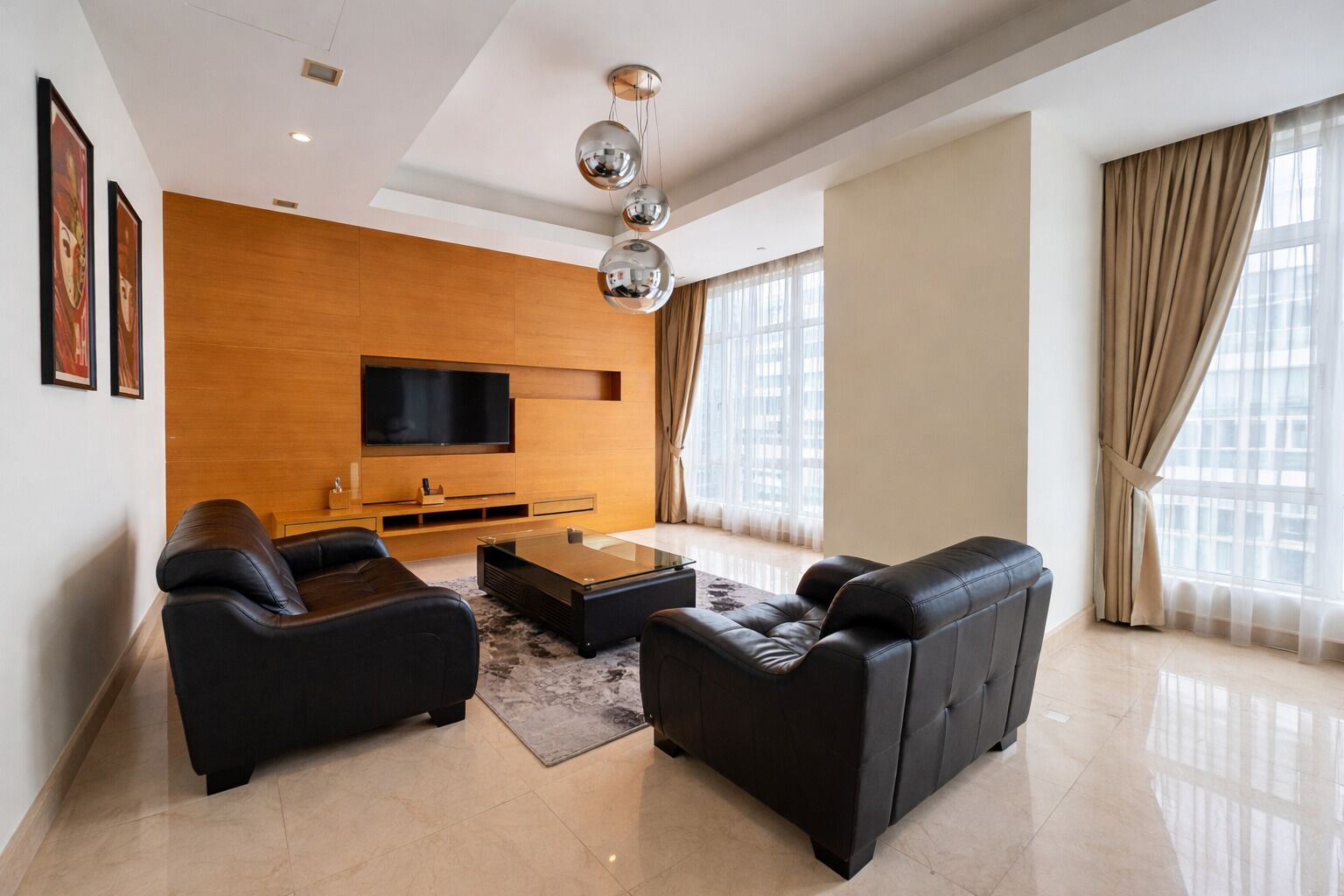 Un salon moderne doté d’un téléviseur à écran plat, de canapés en cuir, d’une table basse et d’un mur décoratif en bois.