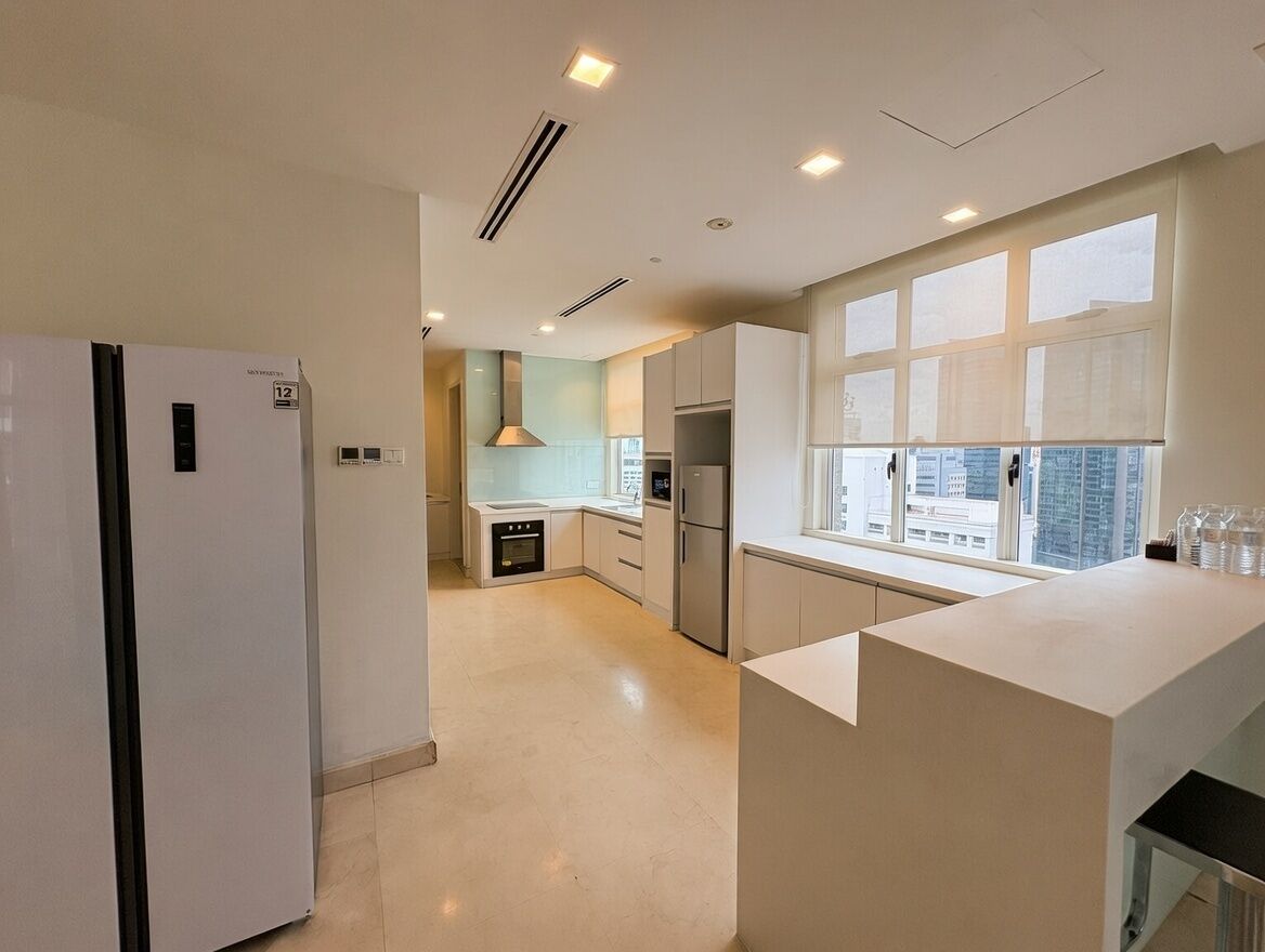 A modern kitchen with white cabinets, a built-in oven, and a large window providing natural light.