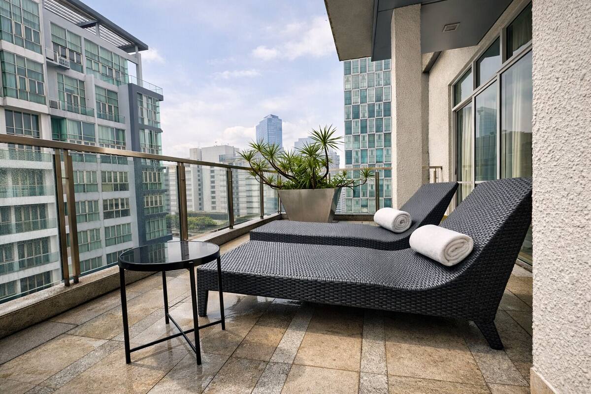 Un balcon avec un fauteuil de relaxation en osier, une petite table et un pot de fleurs.