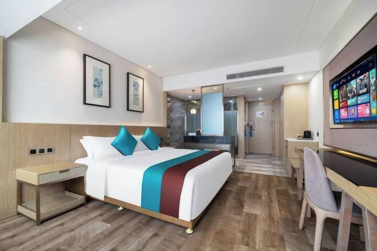 Ein Hotelzimmer mit Bett, Nachttisch, Schreibtisch, Stuhl und Fernseher.