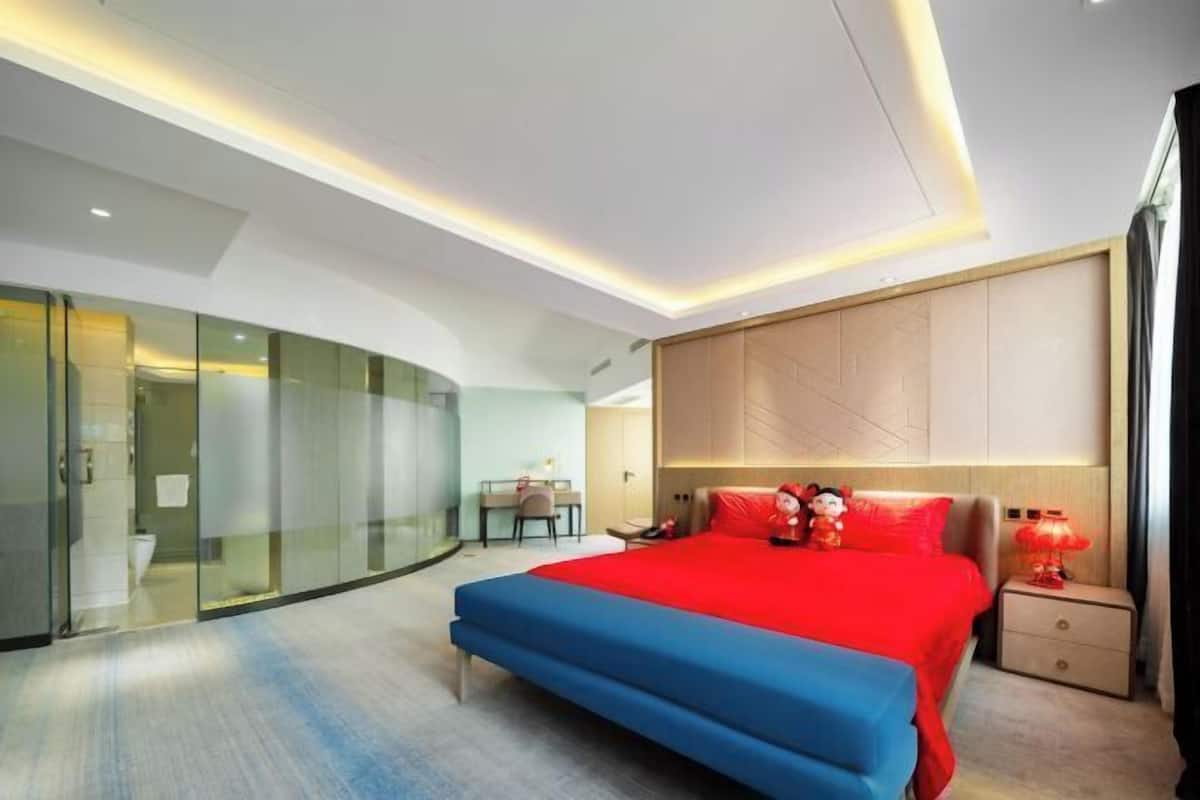 Ein modernes Hotelzimmer mit einem großen Bett, einem Schreibtisch und einer Glastrennwand.