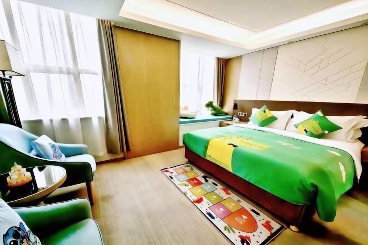 Ein Hotelzimmer mit Bett, Stuhl, kleinem Tisch, Nachttisch und einem Fenster mit Vorhängen.