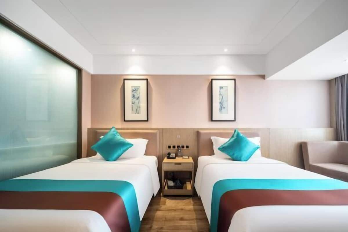 Ein Hotelzimmer mit zwei Betten, einem Nachttisch und Bildern an der Wand.