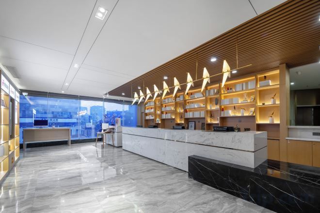 Un moderno vestíbulo de hotel con un mostrador de recepción de mármol, estanterías de madera con libros y vistas a la ciudad.