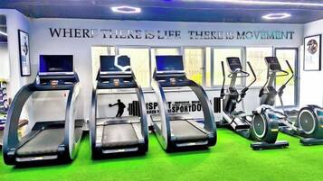 A gym with treadmills, stationary bikes, and a green carpeted floor.