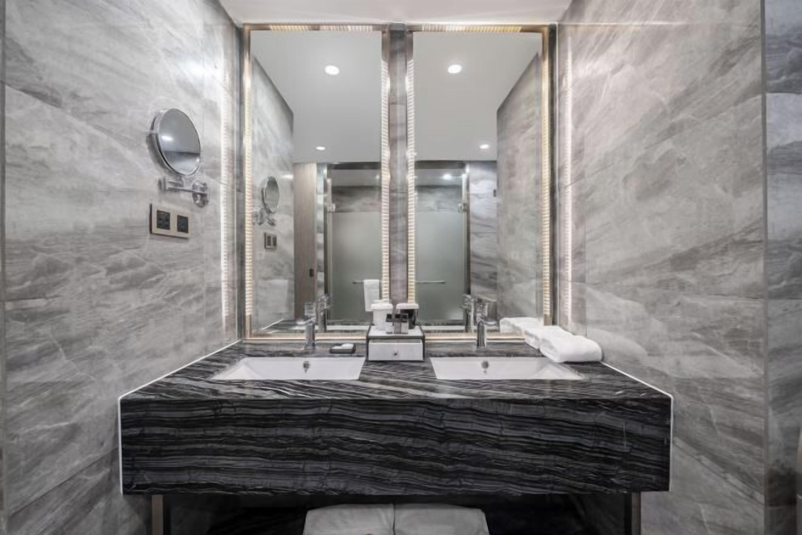 Un baño moderno con un espejo grande, dos lavamanos y un perchero para toallas.