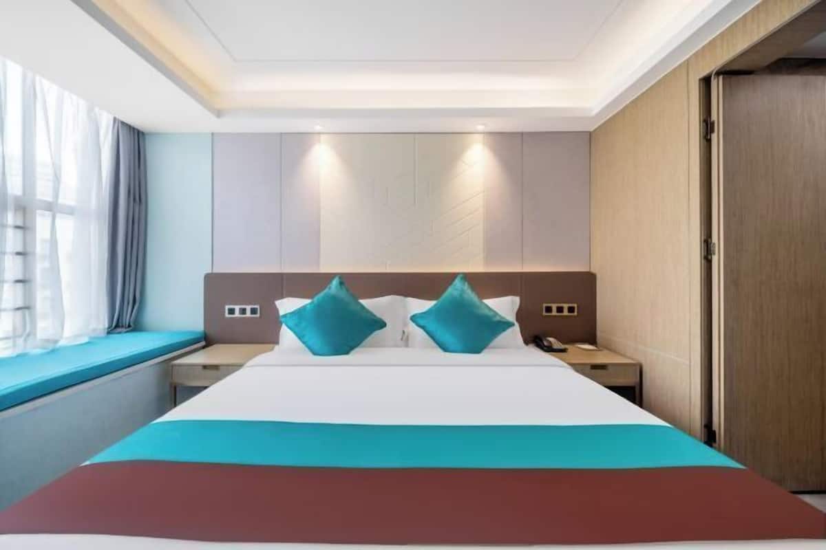 Ein Hotelzimmer mit einem großen Bett, zwei Nachttischen, einem Fenster mit Vorhängen und einem Holzschrank.