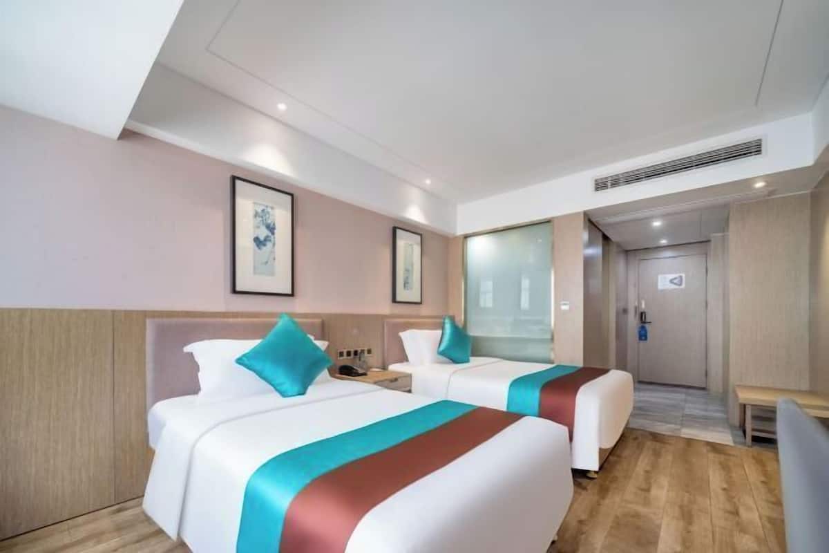 Ein Hotelzimmer mit zwei Betten, Holzboden und einer Tür zum Badezimmer.