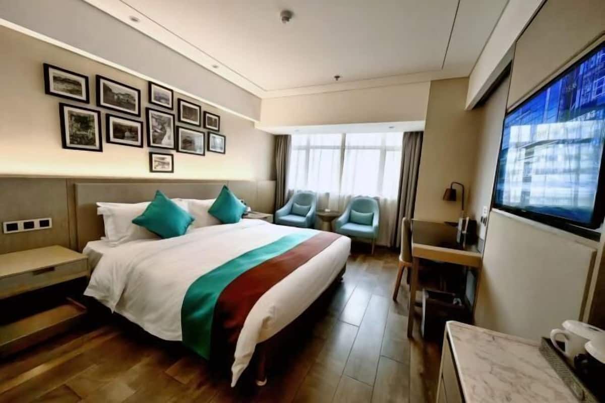 Ein Hotelzimmer mit Bett, Schreibtisch, Fernseher und gerahmten Bildern an der Wand.