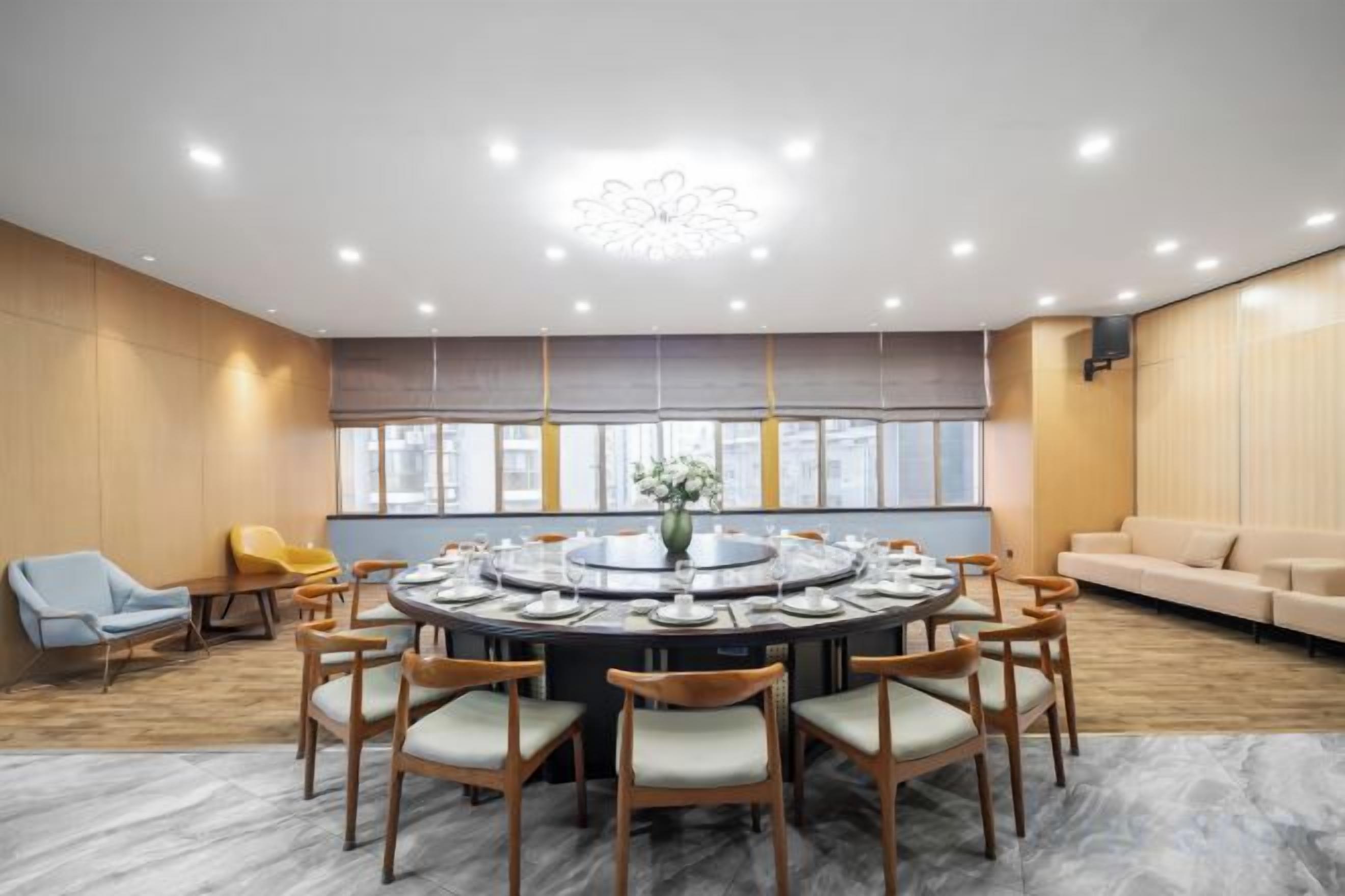 A conference room with a round table, chairs, and a modern ceiling light fixture.