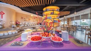 A buffet setup with a central display of books and a decorative tree, surrounded by various food items and dining tables. - Wuhan Zhongshan Park Xuesong Road (Wuhan)