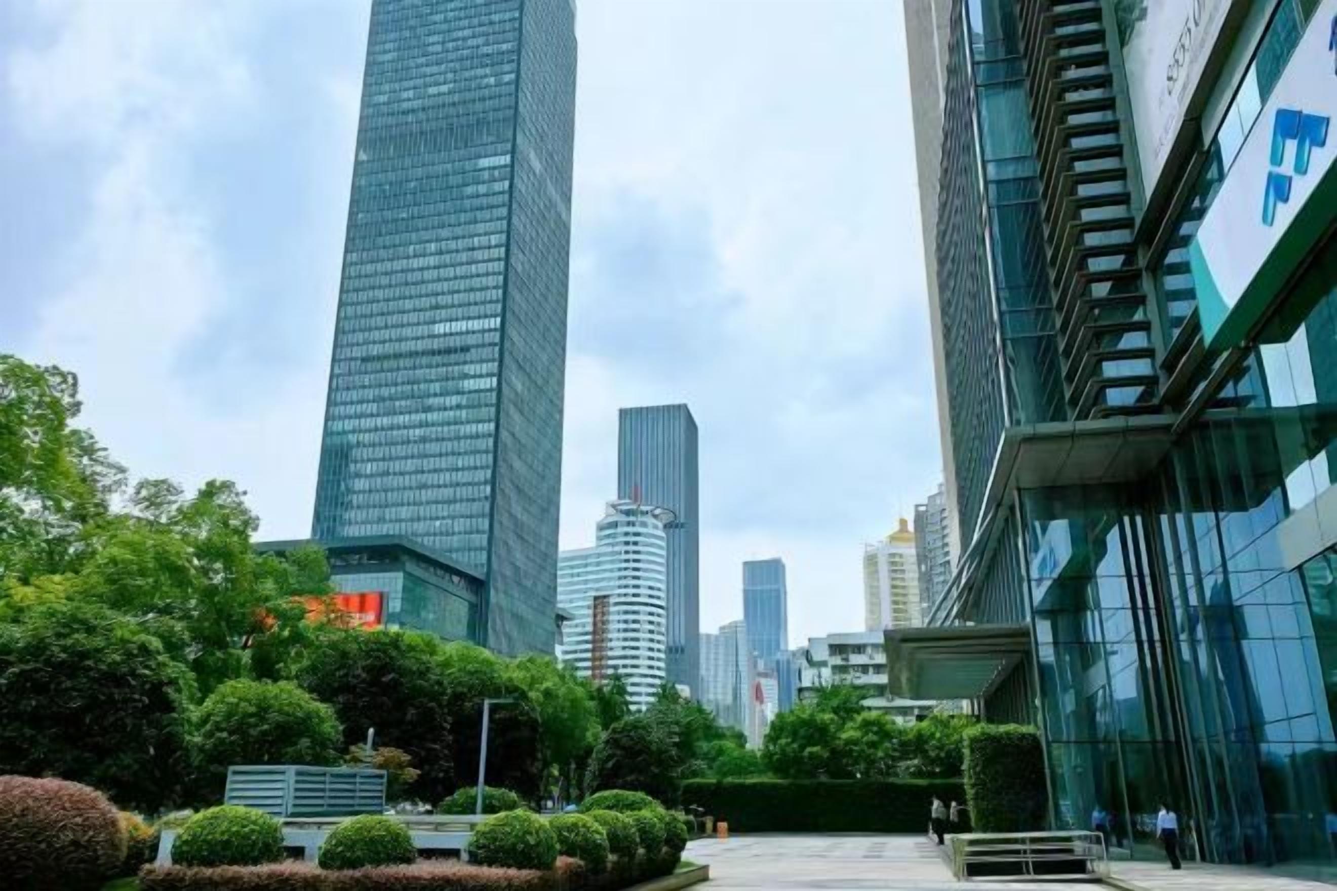 A modern urban landscape with high-rise buildings, a clear sky, and a well-maintained green space.
