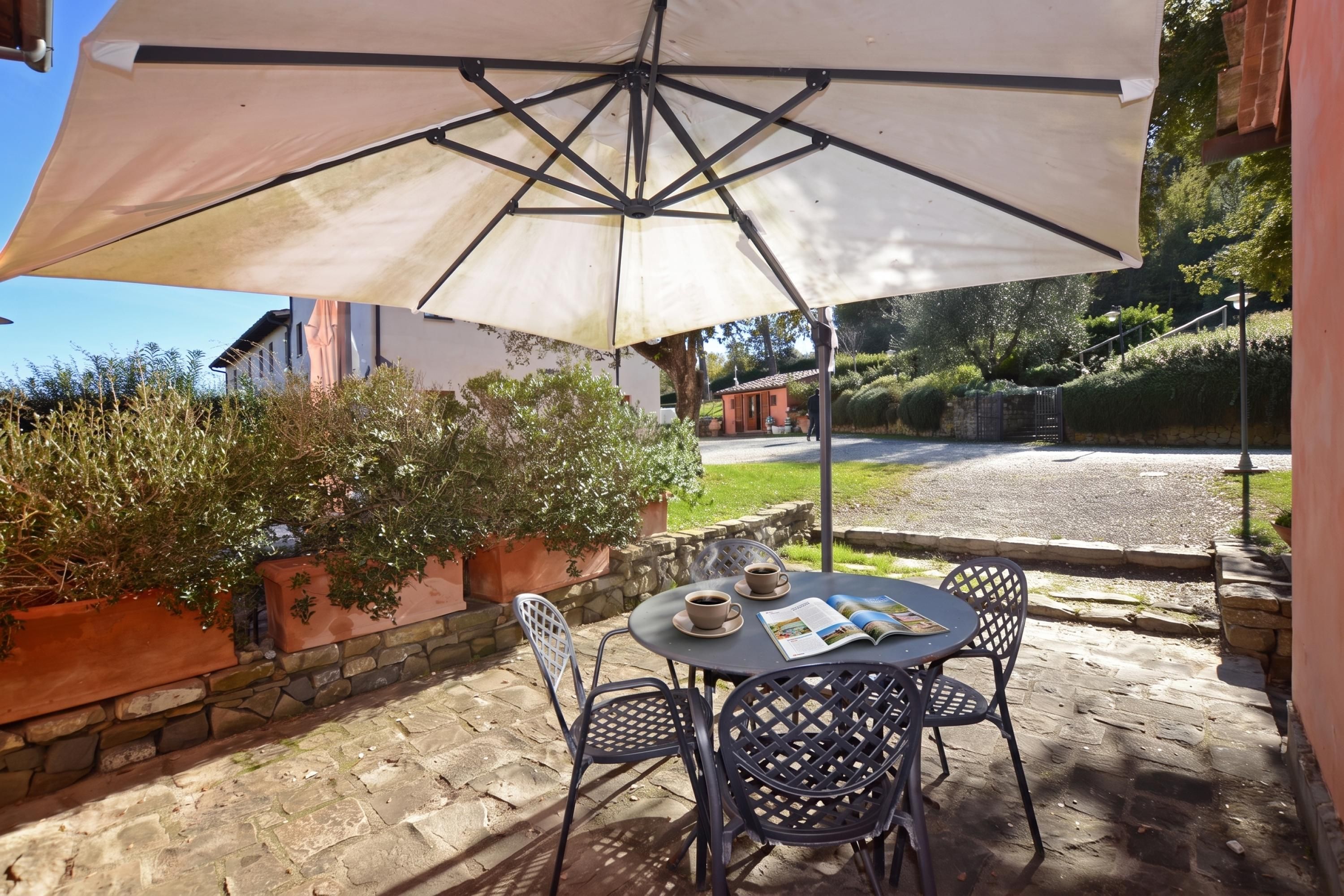 Un patio al aire libre con una mesa, sillas y un paraguas grande.