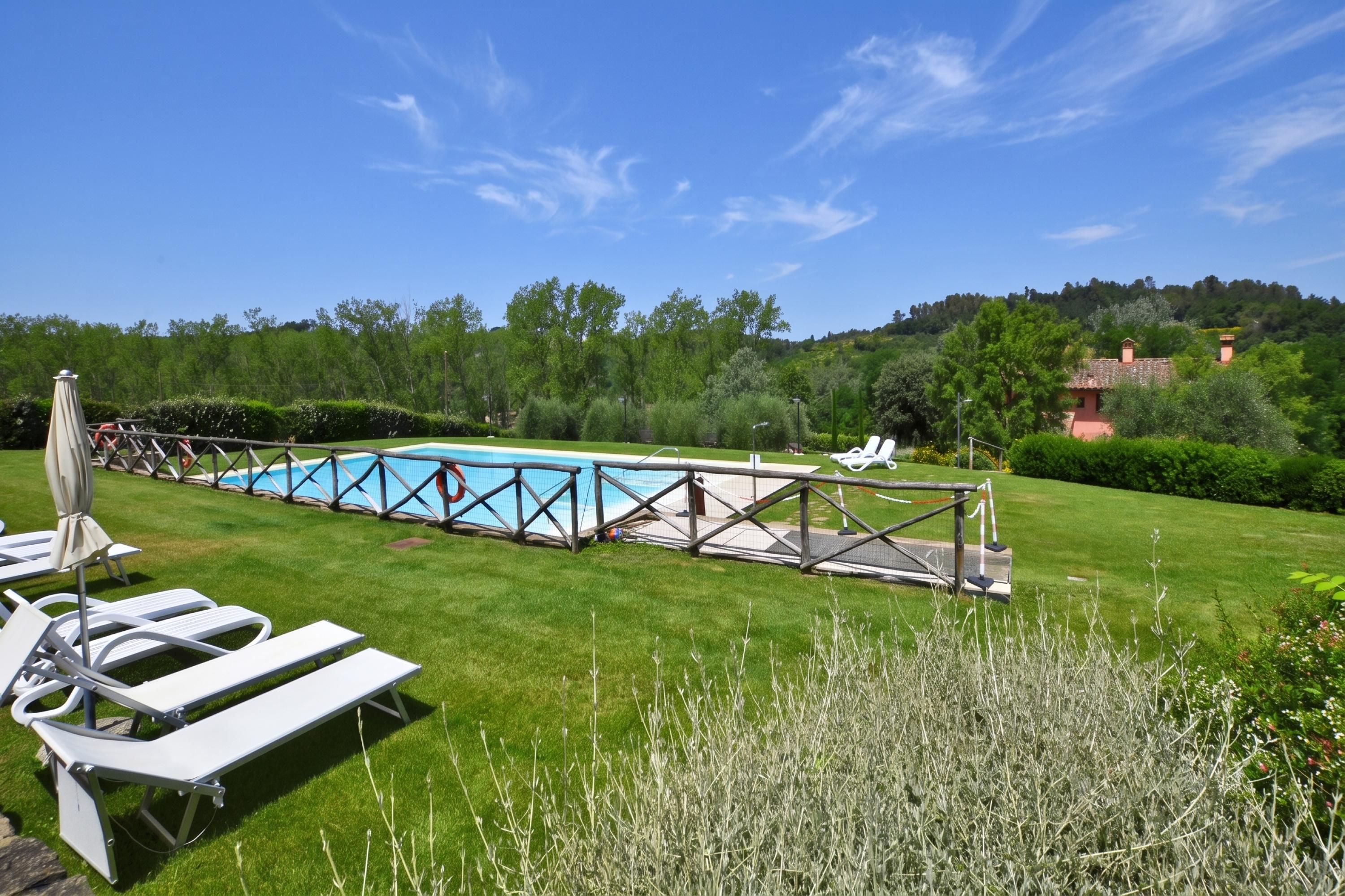 A pool area with lounge chairs and a wooden deck.