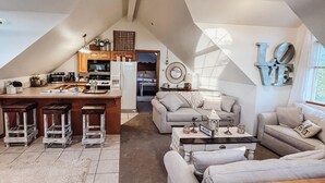 Un espace de vie chaleureux de style loft, comprenant une cuisine, un coin repas et un espace salon.