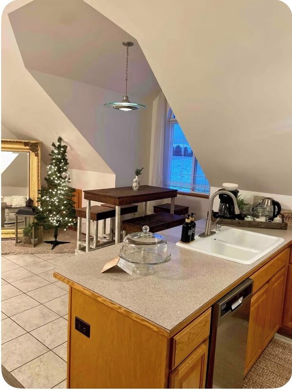 A kitchen with a wooden island, a small Christmas tree, and a dining table. - Country Green Bluff Carriage House with fire pit and pickleball, north Spokane (Colbert)