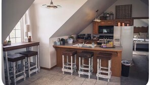 Une cuisine avec un îlot central en bois, des tabourets de bar et un luminaire suspendu.