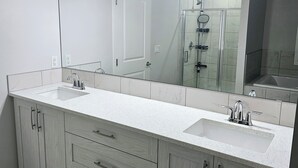 Un baño moderno con un espejo grande, un lavamanos y una ducha.