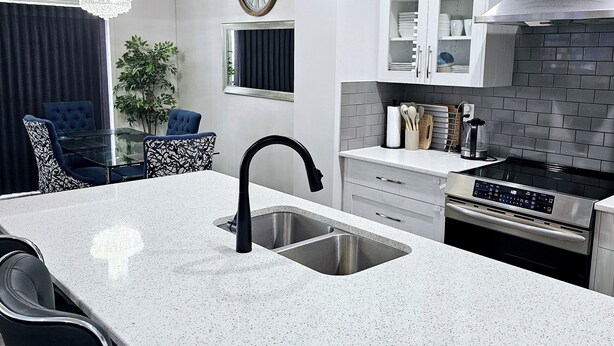 Una cocina moderna con una isla grande, electrodomésticos de acero inoxidable e iluminación colgante.
