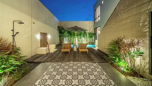 A modern outdoor patio with a pool, wooden furniture, and lush plants. - Villa Noema 2 - Brand New 2BR Villa with Pool (Badung)