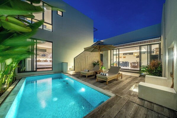 Un espace piscine extérieur moderne offrant une vue dégagée sur la piscine, des chaises longues et un coin salon abrité.