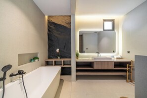 Une salle de bain moderne avec une baignoire sur pieds, un grand miroir et un meuble-lavabo intégré.