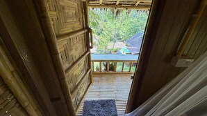 Un escalier en bois mène à un balcon d’où l’on peut admirer les arbres et un bâtiment.