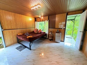 Una habitación con cama, una mesita, un refrigerador y vistas al exterior.