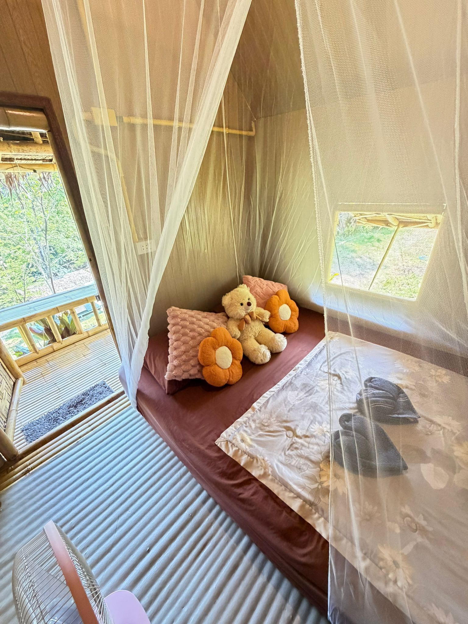 A cozy room with a bed, a window, and a view of greenery outside.