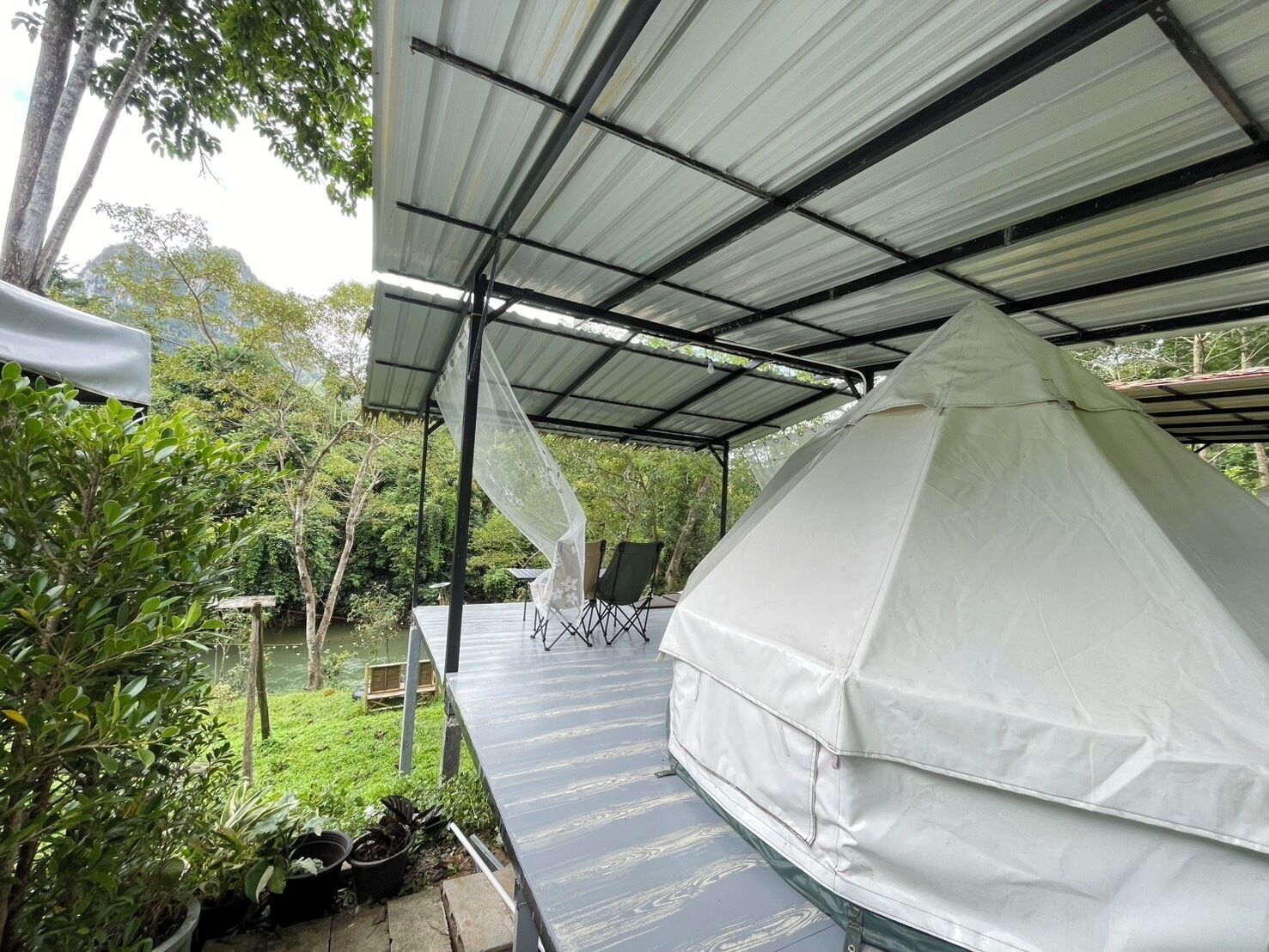 Un espacio al aire libre techado con una carpa blanca y una mesa con sillas.