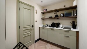 A compact kitchen with a microwave, coffee maker, and utensils on the counter. - Guestready - The Euston Hotel (London)
