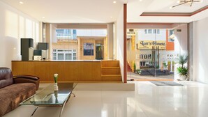 A modern hotel lobby with a reception desk, a sofa, and a glass coffee table. - HANAH HOTEL (Xuan Huong - Da Lat)