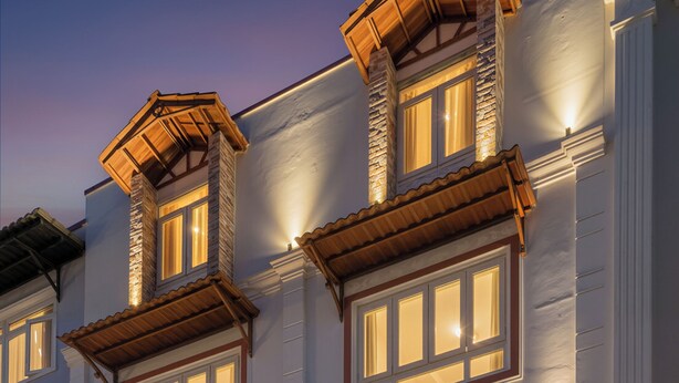A hotel with a modern facade, multiple windows with wooden shutters, and a welcoming entrance with steps and potted plants. - HANAH HOTEL (Xuan Huong - Da Lat)